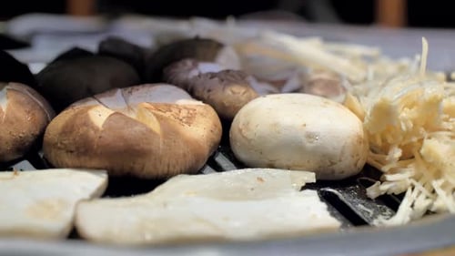 Le cuisinier prépare des champignons sur une assiette barbecue coréenne