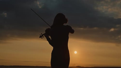 Violinist Plays at Sunset by the Water
