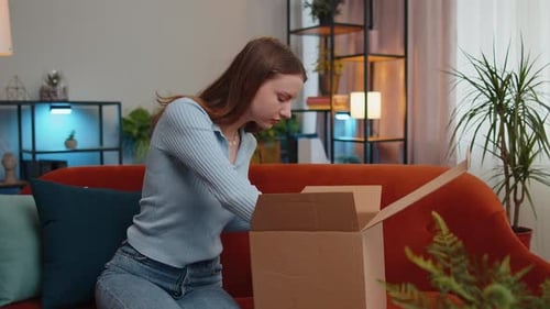Young Woman Opening Cardboard Box with Unhappy Expression