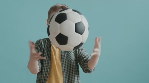 Smiling Boy Hugs Soccer Ball Indoors