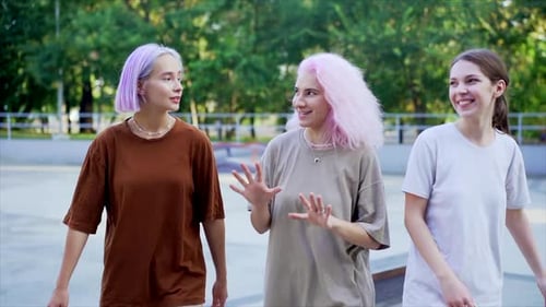 Happy Teenage Girls Walking Outdoors in Green Skate Park. Friends Having Fun, Laughing, Holding