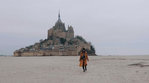 Wide Shot Beautiful Happy Tourist Woman Slowly Walking on Low Tide Sea Sand at Epic Mont Saint