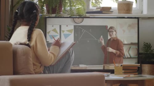 Child Attends Online Class at Home, Writing in Notebook