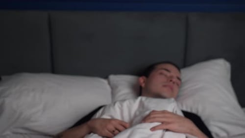 Vue de face : Un jeune homme caucasien choqué dort trop longtemps en se levant vite alors qu'il est couché