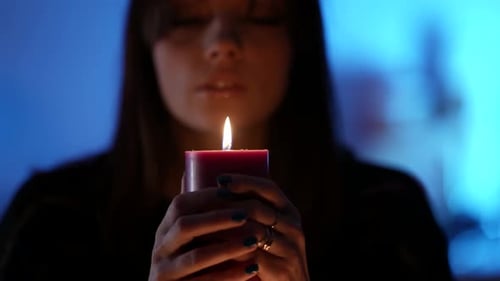 Woman Holds Burning Candle in Dark, Intimate Setting