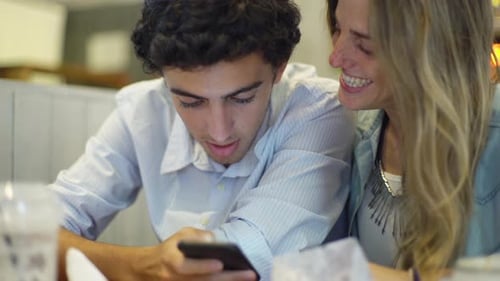 Couple Laughing Together Looking at Phone