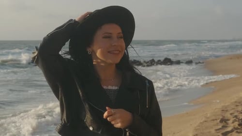 Portrait of Romantic Brunette Woman in Hat and Leather Jacket Walking on the Beach in Autumn at