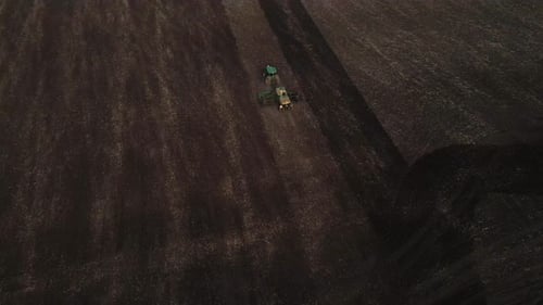 Aerial view, drone view of green tractor with plough working on a field,