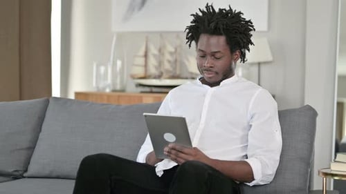 Young Adult Using Tablet at Home on Couch