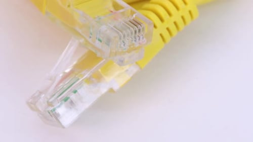 Ethernet yellow cable rotating on white surface, close up view from above in 4k.