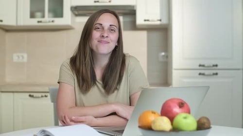 Woman Smiles At Table With Laptop and Fruit