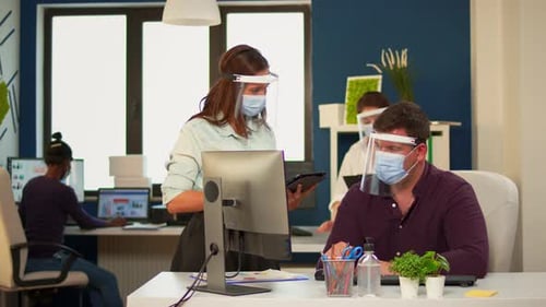 Employees Using Technology in Office Wearing Face Shields