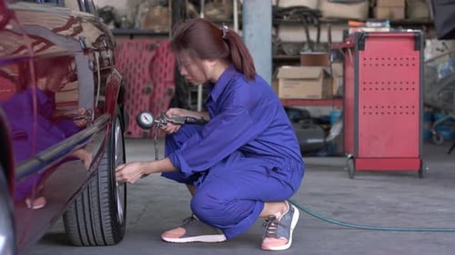 Woman inflating car tire in garage