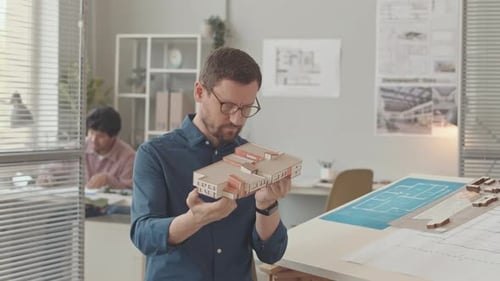 Architect Holding Building Model in Office