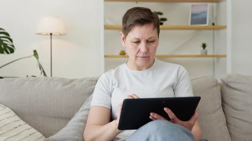 Woman Using Tablet on Couch in Home