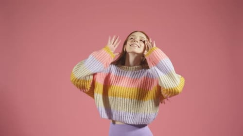 Smiling Woman Poses in Striped Sweater on Pink