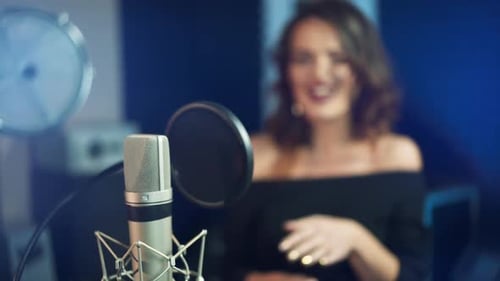 Professional microphone in the recording studio. Singing woman in the background