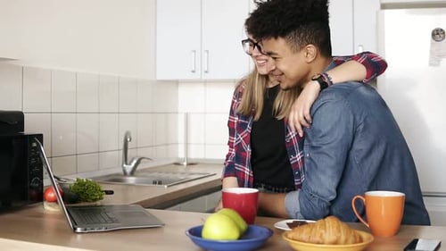Happy Couple Video Chatting on Laptop in Kitchen