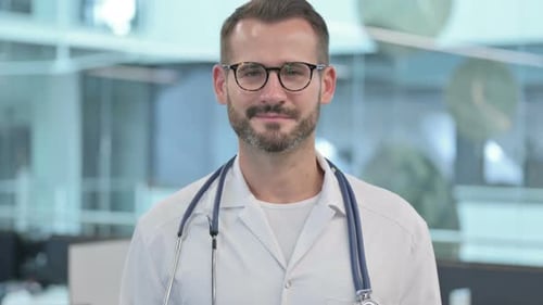 Männlicher Arzt mittleren Alters schüttelt Kopf als Ja-Zeichen