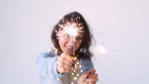 Smiling Woman Celebrating with Sparklers and String Lights