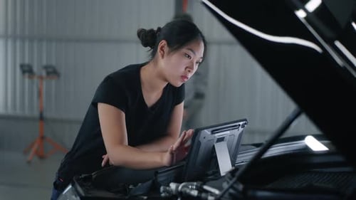 Female Mechanic Checking Car with Tablet
