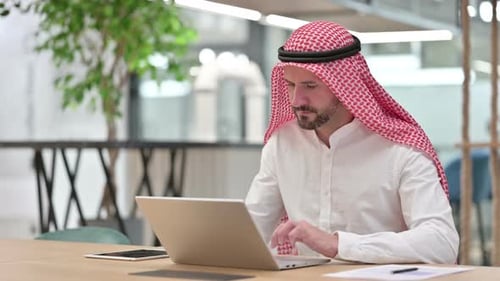 Thumbs Down By Serious Arab Businessman with Laptop