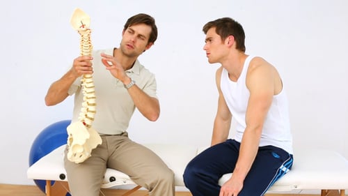 Man Explains Spine Model to Patient in Clinic