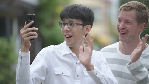 Two Happy Multi-ethnic Businessmen Video Calling Together in the Streets Outdoors