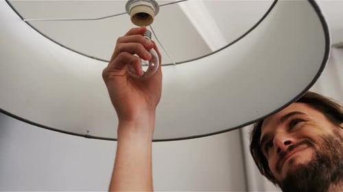 Mann installiert eine Glühbirne im Wohnzimmer