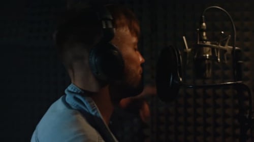 Young Adult Singing into Microphone in Recording Studio