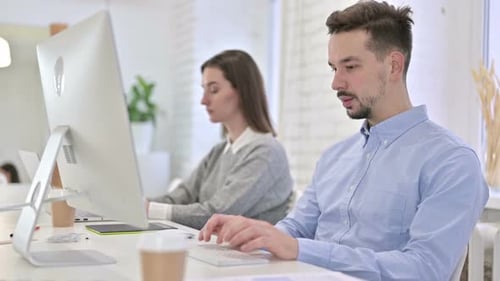 Focused Creative Team Working on Desktop in Modern Office