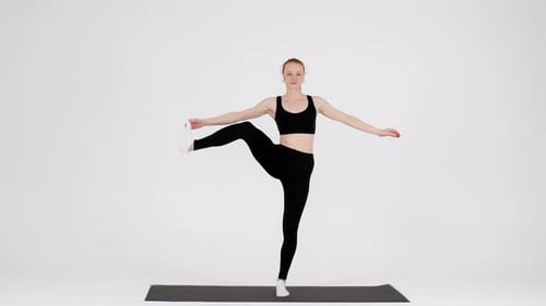Young Flexible Woman Practicing Yoga In Studio Lifting Leg Aside