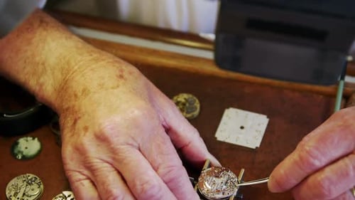 Gros plan des mains d'un horloger réparant une montre