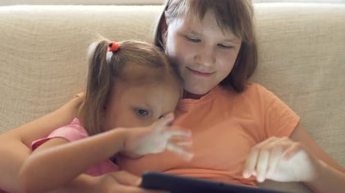 Two Girls Using Tablet Together on Couch