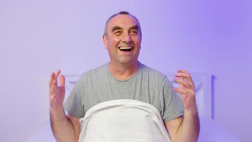 Happy Adult Man Sits Up and Laughs