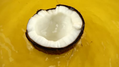 Halved Coconut Floating in a Yellow Liquid