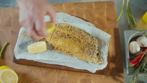 Fried Fish Being Garnished with Lemon and Onions