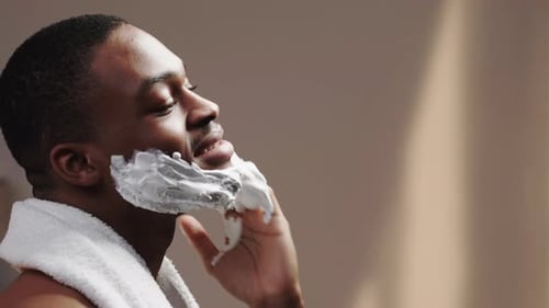 Cuidado facial para hombre, afeitado, hombre africano, aplicando espuma