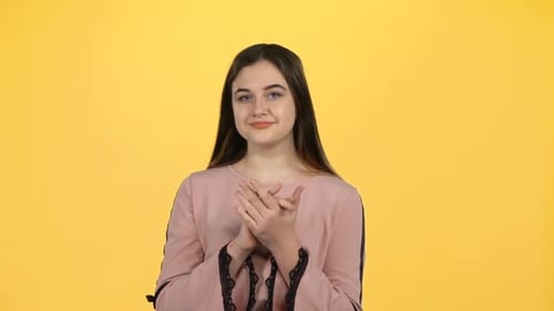 Woman Smiling and Clapping Hands on Yellow Background