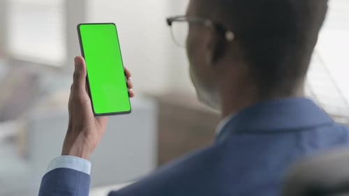 Man Holding Smartphone with Green Screen Indoors