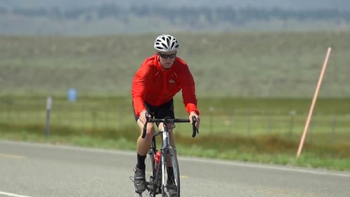 A man road biking on a scenic road.