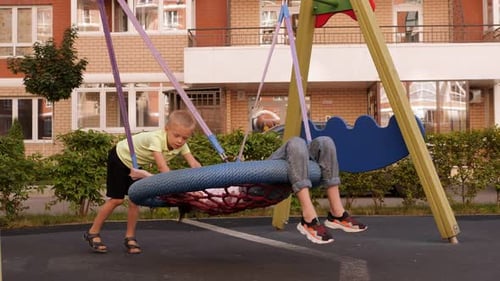 Boy Pushes Girl on a Playground Swing
