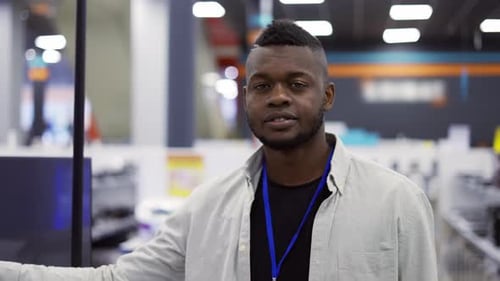 Smiling Salesman Showing Tv Stands Among Appliances in a Store Slowmotion Video