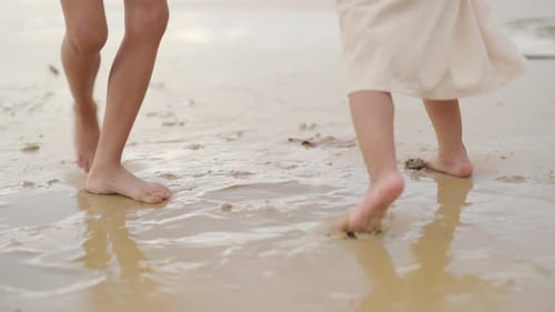 4K Little Asian child boy and girl sibling playing together on the beach at summer sunset.