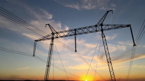 Dark Silhouette of High Voltage Tower with Electric Power Lines at Sunrise