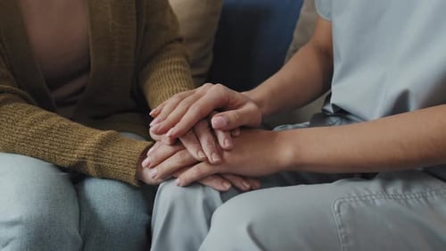 Nahaufnahme von Krankenschwester und Seniorin beim Händchenhalten