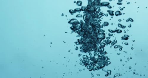 Bubbles Falling And Rising In Water Against Blue Background
