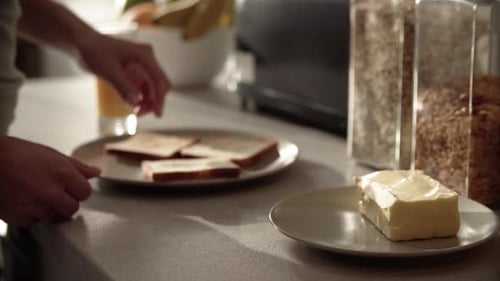 Person Buttering Toast in Morning Kitchen