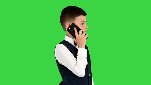Serious Boy in a White Shirt Bow Tie and Vest Talking on the Phone on a Green Screen Chroma Key