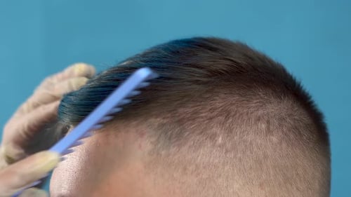 Un joven de cabello azul se peina. Hombre alternativo en un salón de belleza en un azul